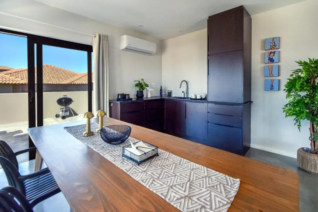 Modern dining and kitchen area with wooden table and dark cabinetry