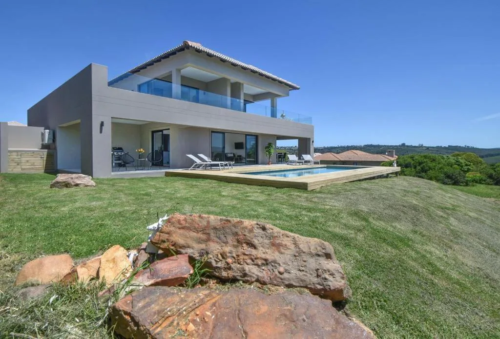 Modern villa with pool overlooking lush green hills and distant landscape