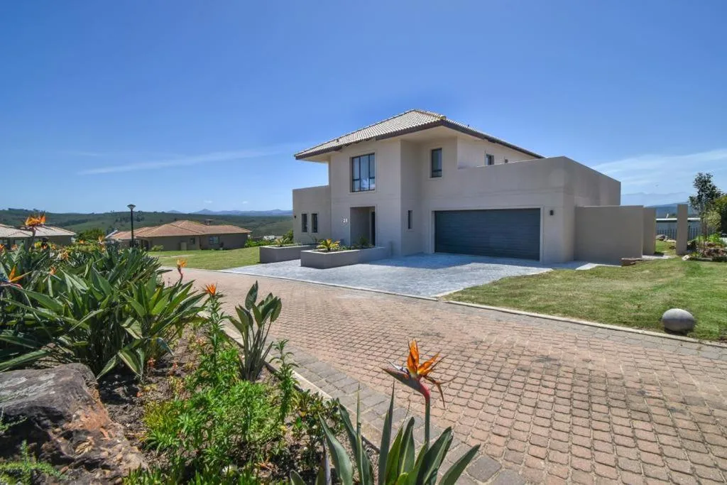 Modern cream villa with garage, brick driveway, mountain views, lush gardens