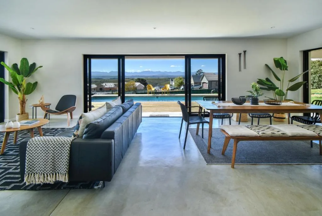 Modern lounge with black sofa overlooking pool and mountain views through large windows