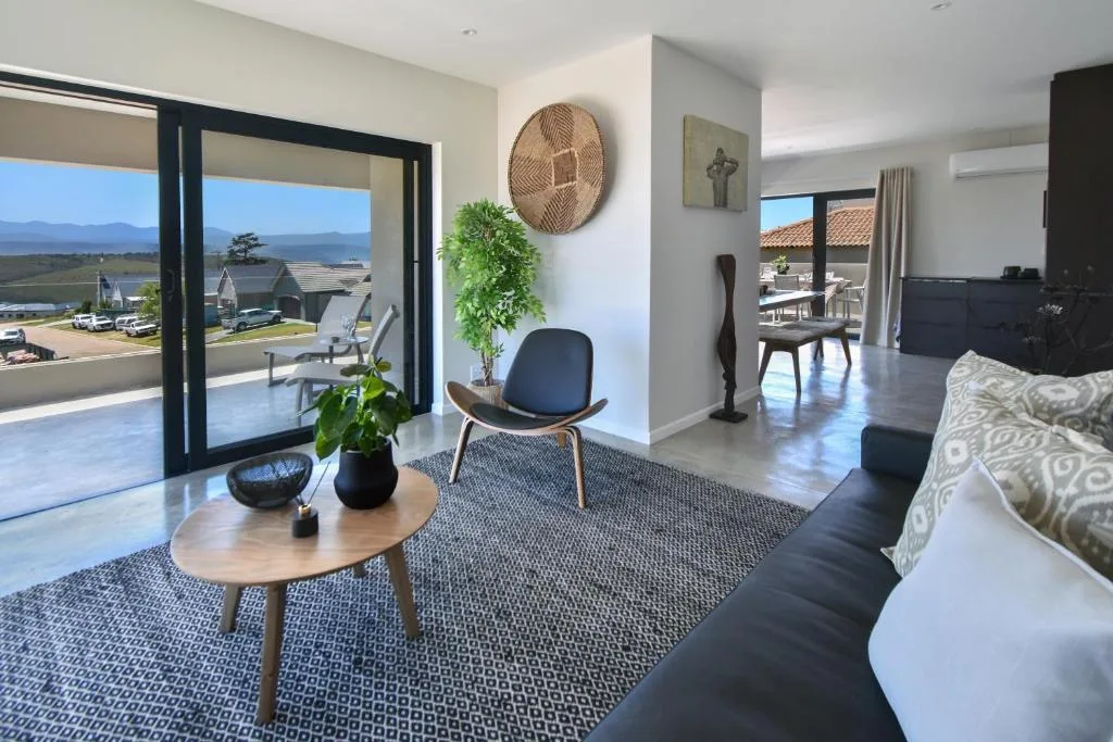 Modern lounge with sofa, chair, and lagoon views through large windows