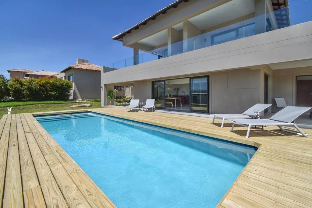 Swimming pool with wooden deck and loungers beside modern villa