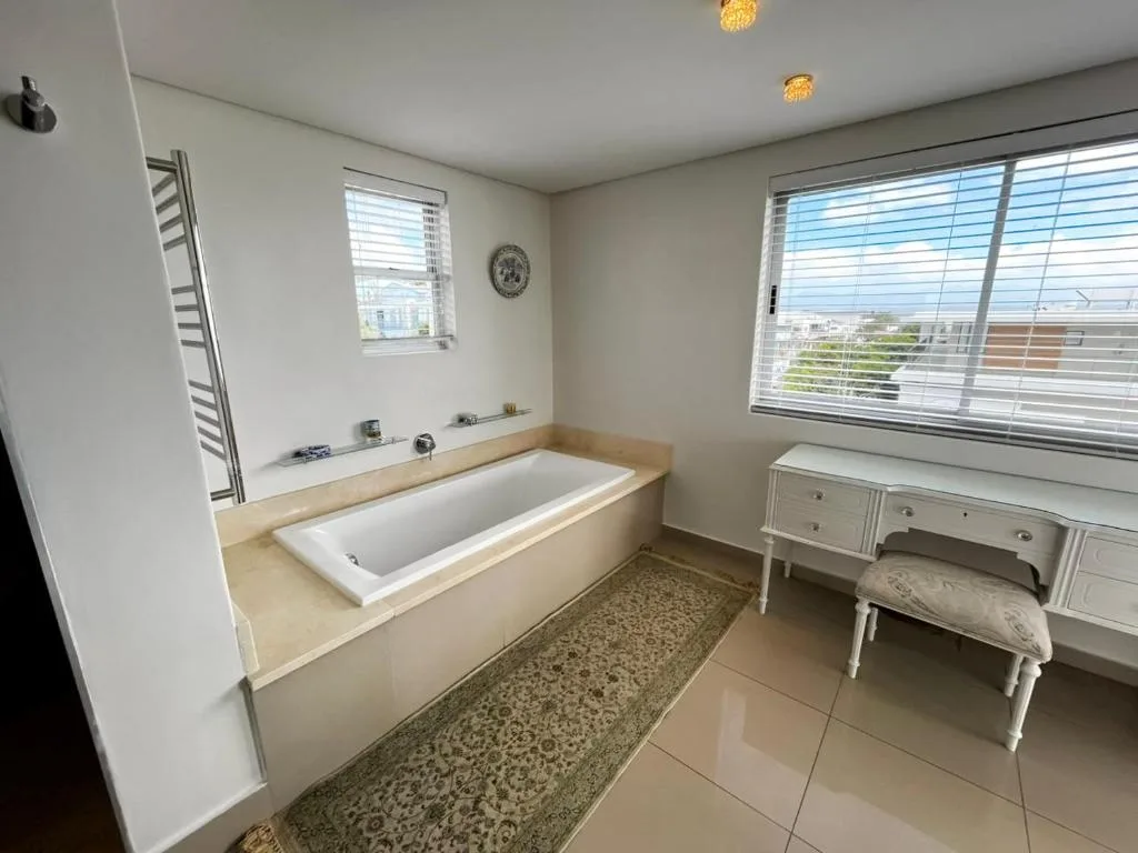 Spacious bathroom with sunken bathtub, vanity, and large windows overlooking Plettenberg Bay