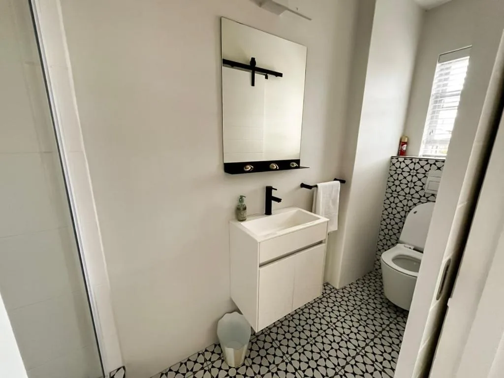 Modern bathroom with white vanity sink, black tap, and patterned floor tiles