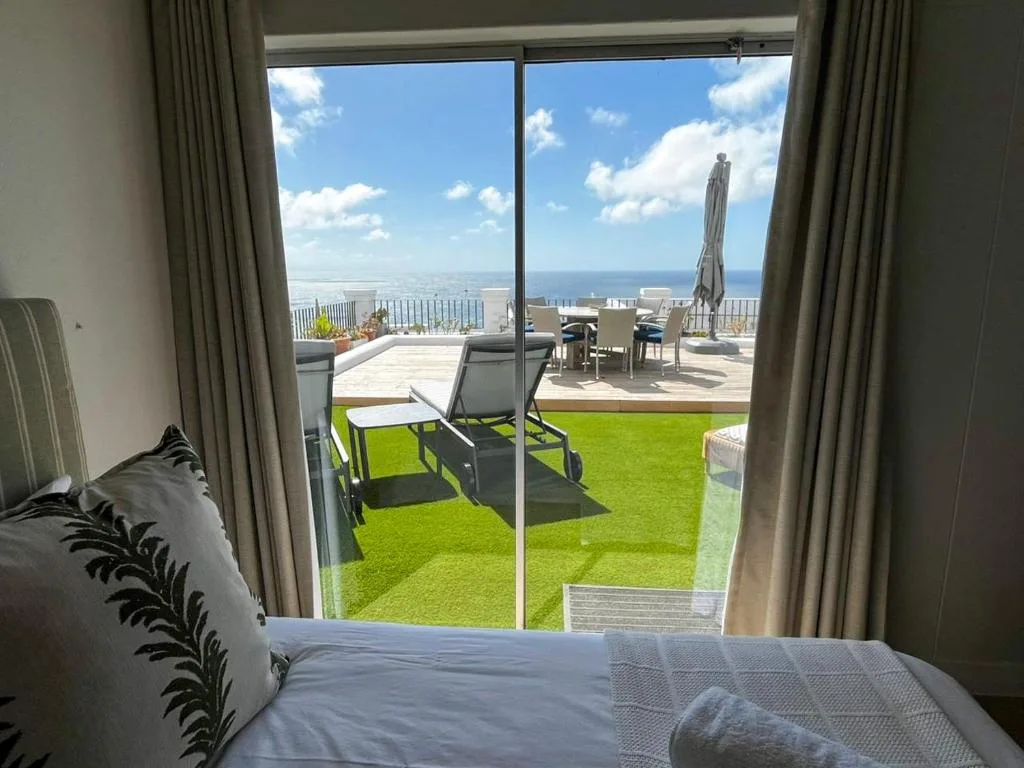 Bedroom with ocean view through glass doors to seaside deck