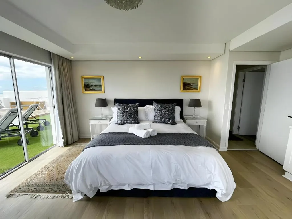 Spacious modern bedroom with king bed, ocean view through glass doors
