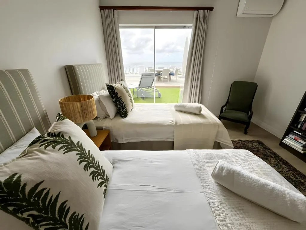 Bright bedroom with twin beds, ocean views through glass doors to deck area