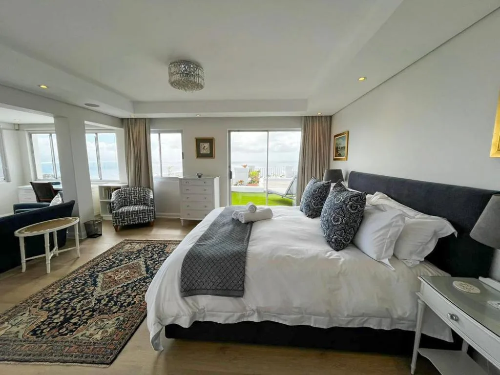 Spacious master bedroom with ocean views through sliding doors and deck access