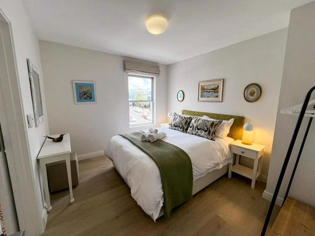 Bright bedroom with queen bed, green throw, and garden view window