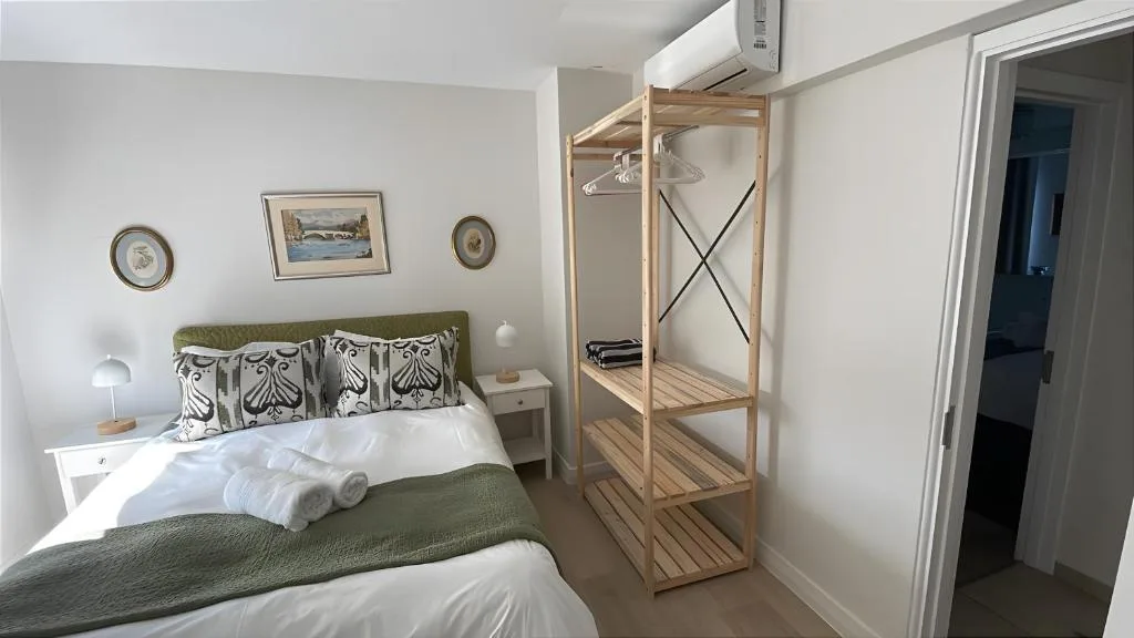Bright bedroom with queen bed, green headboard, wooden wardrobe, and coastal decor
