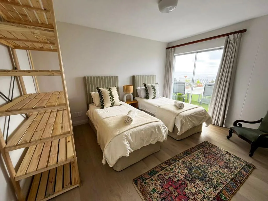 Bright bedroom with two single beds, wooden ladder, and garden views