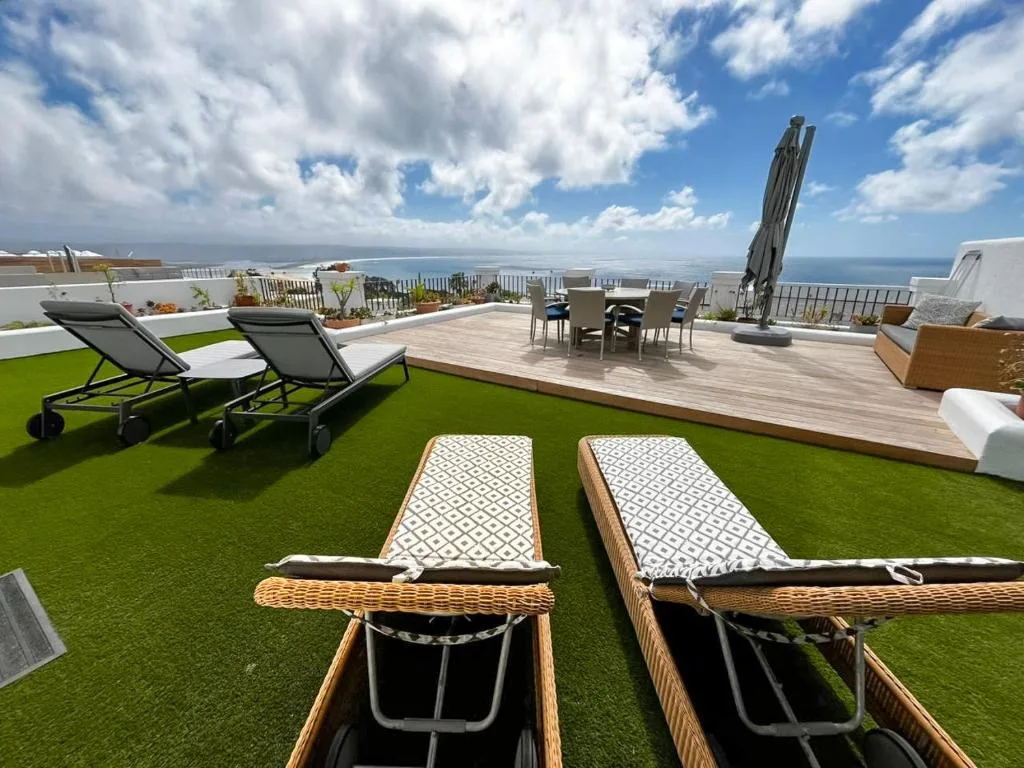 Spacious rooftop deck with loungers, seating area, and panoramic ocean views
