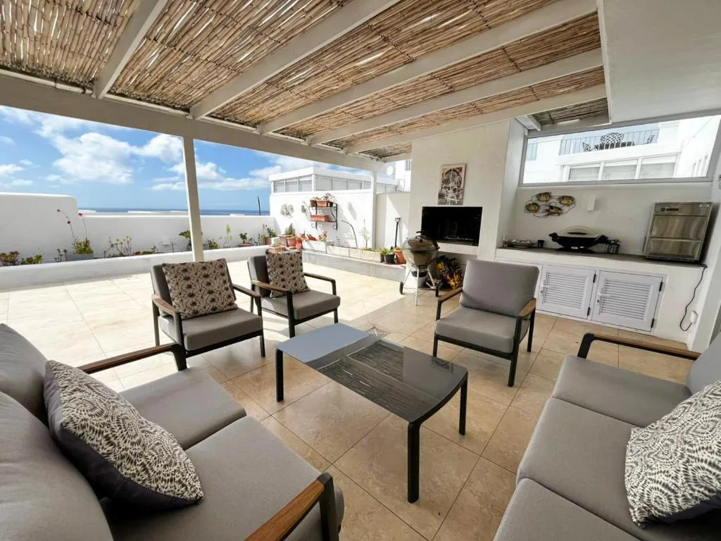 Covered outdoor terrace with seating, ocean views, and entertainment kitchen