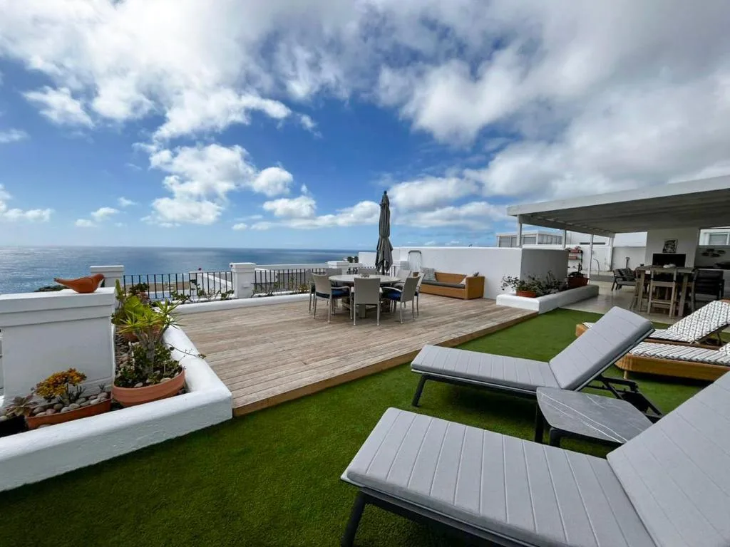 Expansive rooftop deck with loungers, dining area, and ocean views