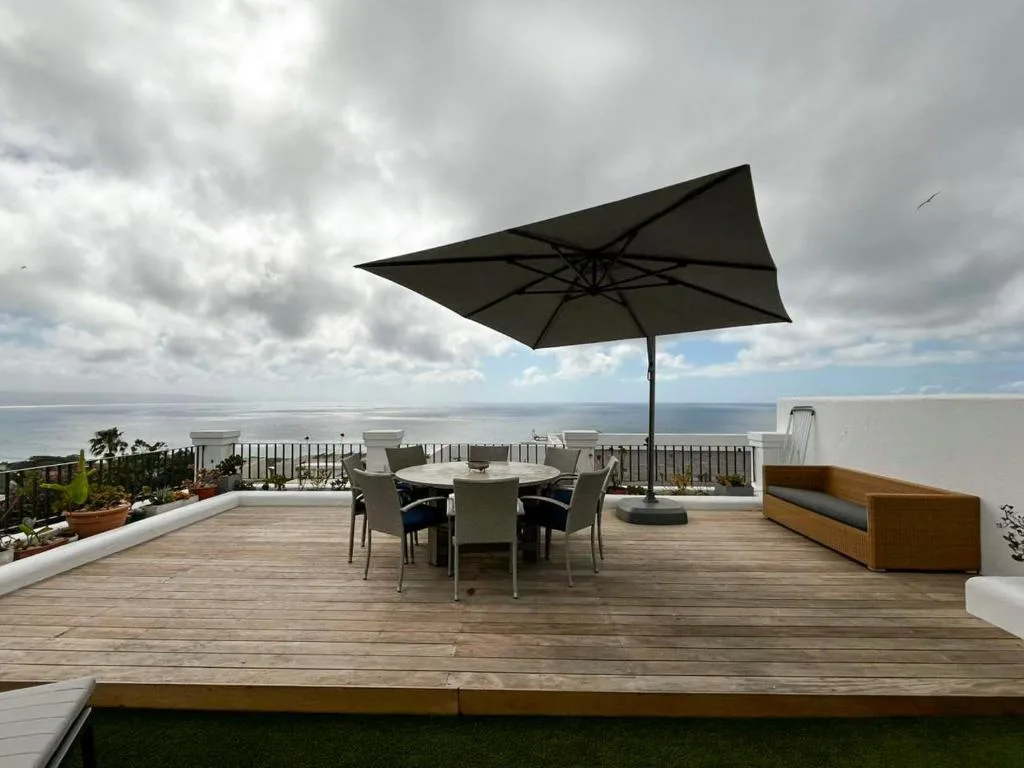Spacious rooftop deck with dining table, umbrella, and ocean views