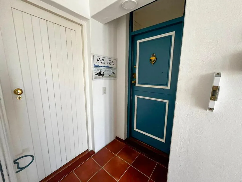 Teal entrance door with white trim and brass hardware in hallway