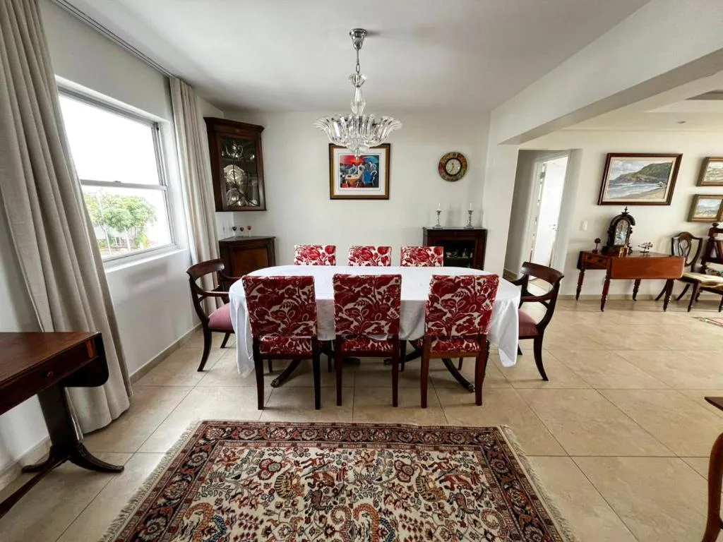 Elegant dining room with round white table and red patterned chairs