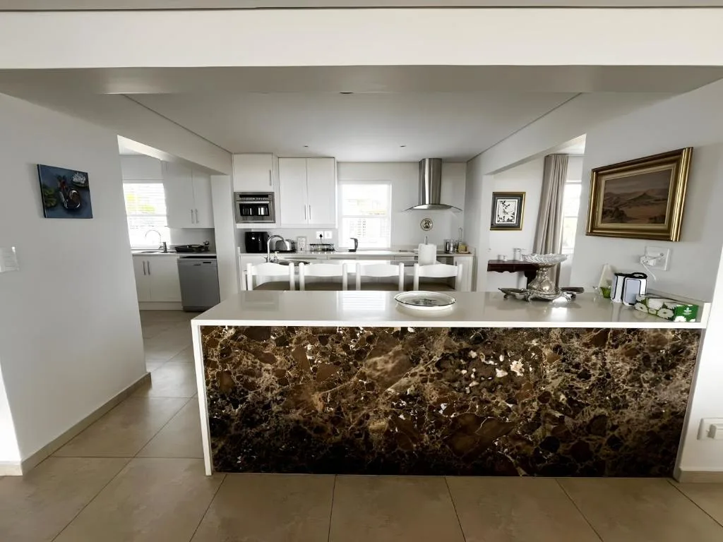Modern open-plan kitchen with white cabinetry and marble island countertop