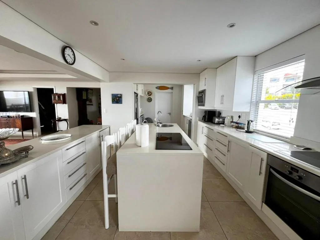 Modern white kitchen with island bench, stainless steel appliances, and natural light