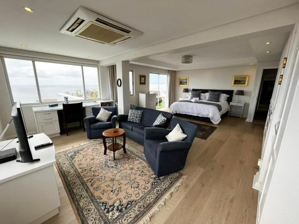 Spacious penthouse lounge with ocean view, navy sofa, and bedroom area beyond