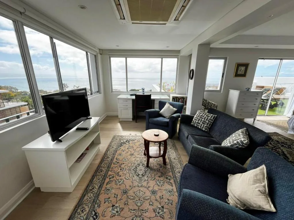 Bright lounge with ocean views, navy sofa, TV, and large windows