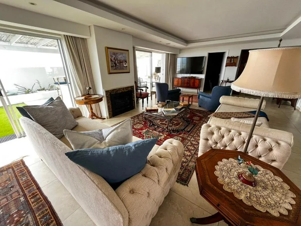 Spacious lounge with cream sofas, fireplace, and ocean views through glass doors