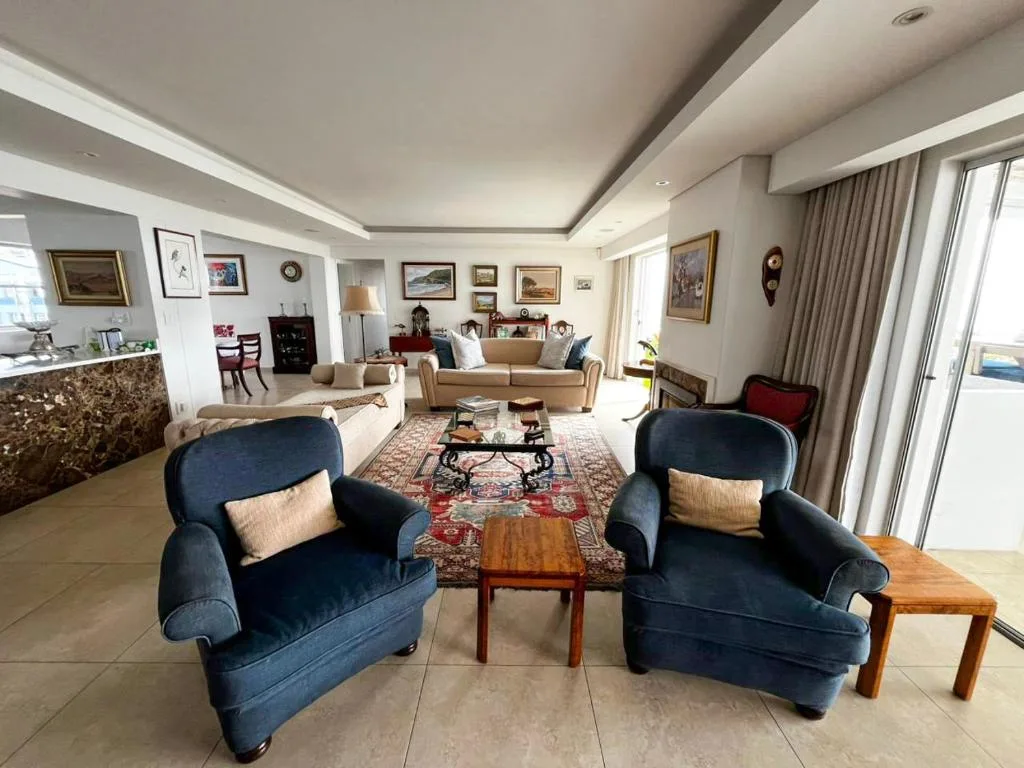 Spacious living room with blue armchairs, beige sofa, and framed artwork
