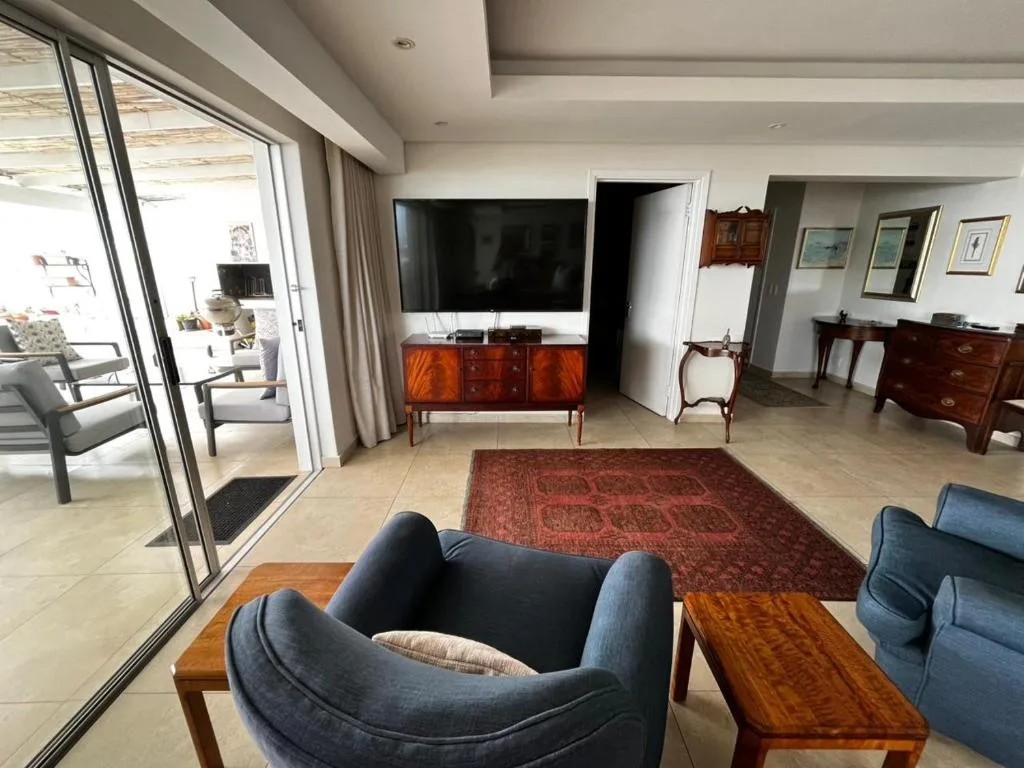 Modern living room with blue armchairs, TV, and sliding glass doors to deck