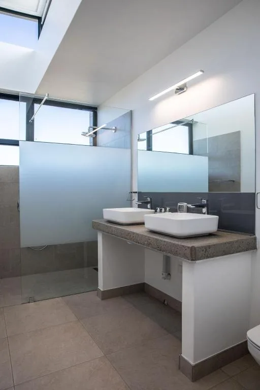 Modern bathroom with dual white vessel sinks and frameless shower enclosure