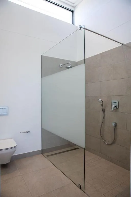 Modern bathroom with walk-in shower, glass partition, and tiled walls