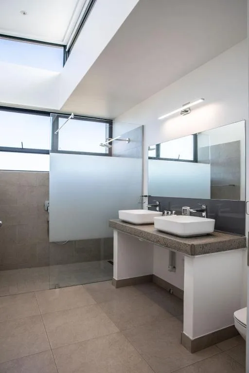 Modern bathroom with double vanity, vessel sinks, and walk-in shower