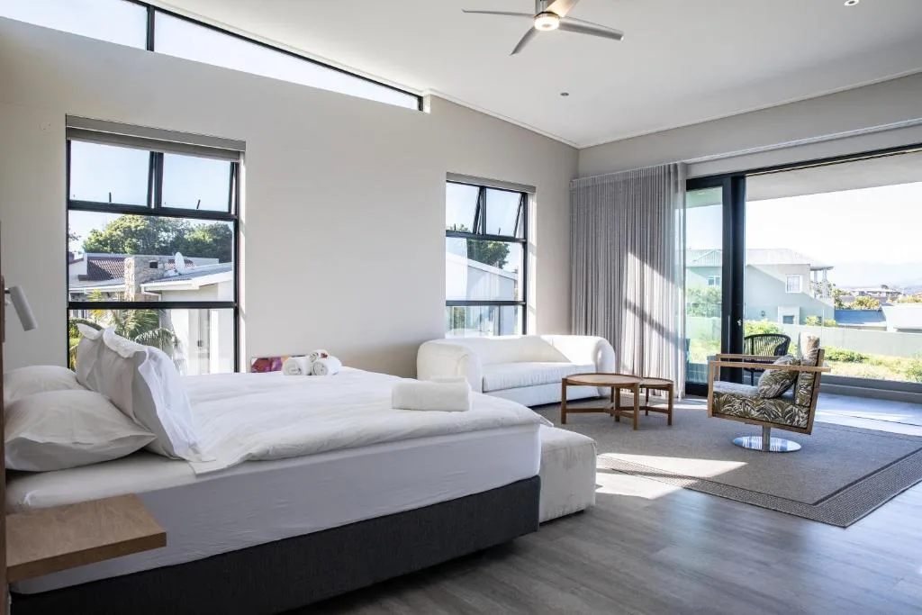 Spacious modern bedroom with two beds, sitting area, and panoramic bay views