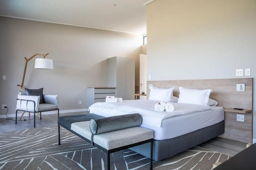 Spacious modern bedroom with king bed, reading chair, and natural light