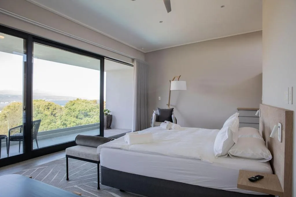 Spacious bedroom with ocean view through sliding glass doors and modern furnishings