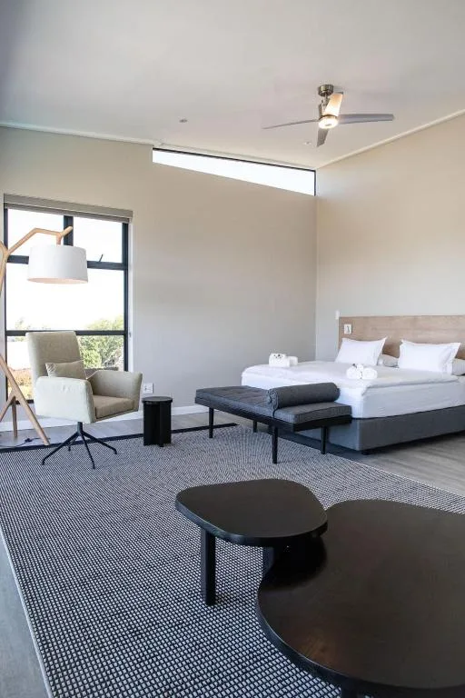 Modern bedroom with queen bed, seating area, and large windows with natural light