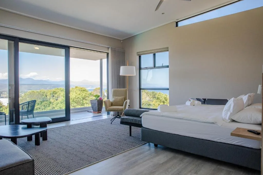 Spacious bedroom with ocean and mountain views from floor-to-ceiling windows