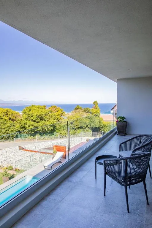Modern balcony with seating overlooking ocean and beach landscape
