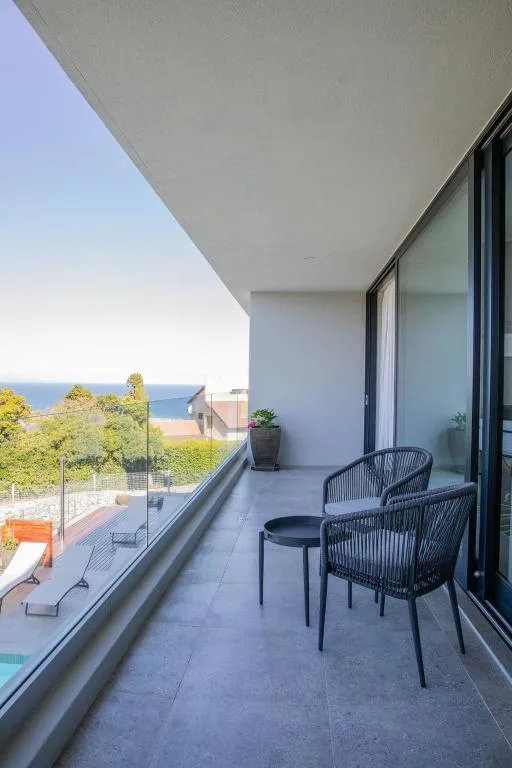 Modern balcony with seating overlooking bay and coastal landscape