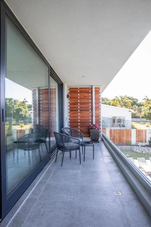 Modern covered balcony with seating chairs overlooking gardens and landscape