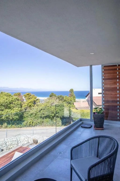 Oceanview deck with modern furniture and glass railing overlooking coastal landscape
