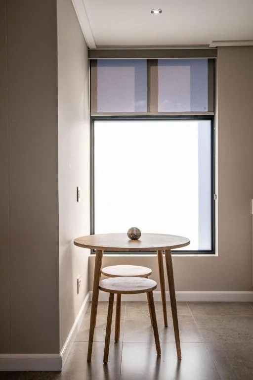 Modern round wooden table with stool near bright window opening