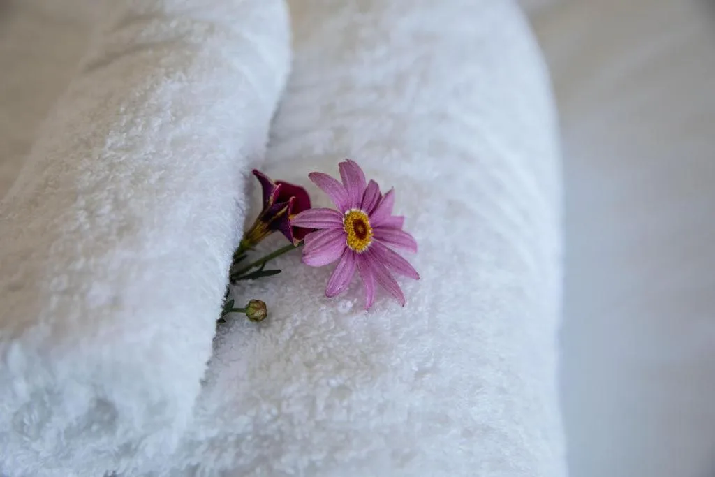 Pink flowers arranged on folded white towels, spa amenity detail
