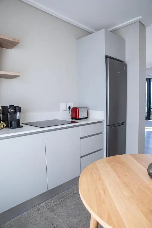 Modern white kitchen with black refrigerator and coffee maker appliances