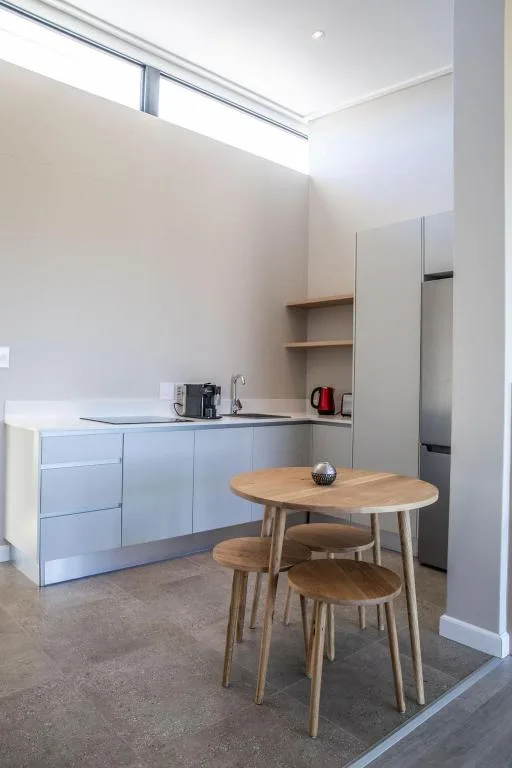 Modern kitchen with light blue cabinetry, dining table, and skylights