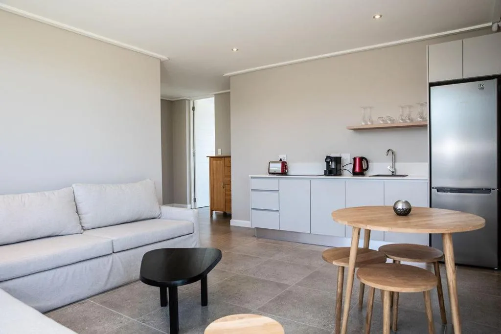 Modern open-plan lounge with light gray sofa and round dining table