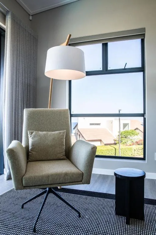 Modern lounge corner with comfortable armchair and floor lamp overlooking garden