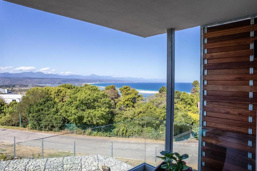 Blue ocean and mountain vista from covered deck overlooking lush vegetation
