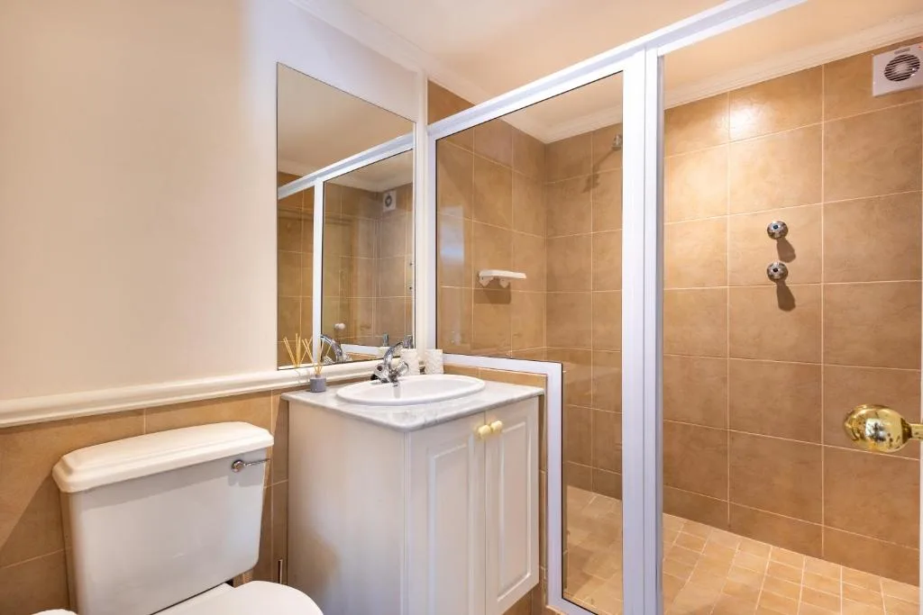 Modern bathroom with vanity, toilet, and walk-in shower with glass enclosure