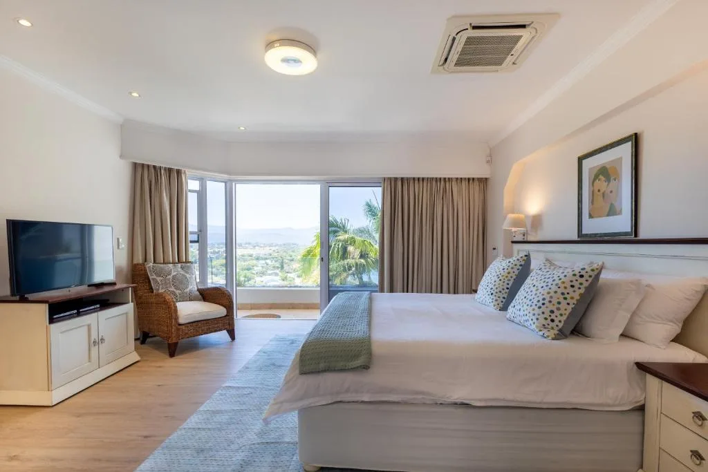 Spacious bedroom with king bed, TV, and panoramic garden route views