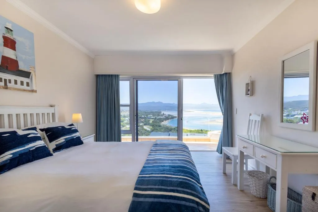 Spacious bedroom with ocean and mountain views through glass doors